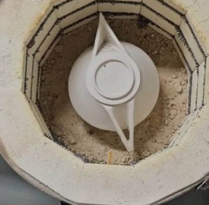 Une théière blanche dégourdie au fond du four ouvert