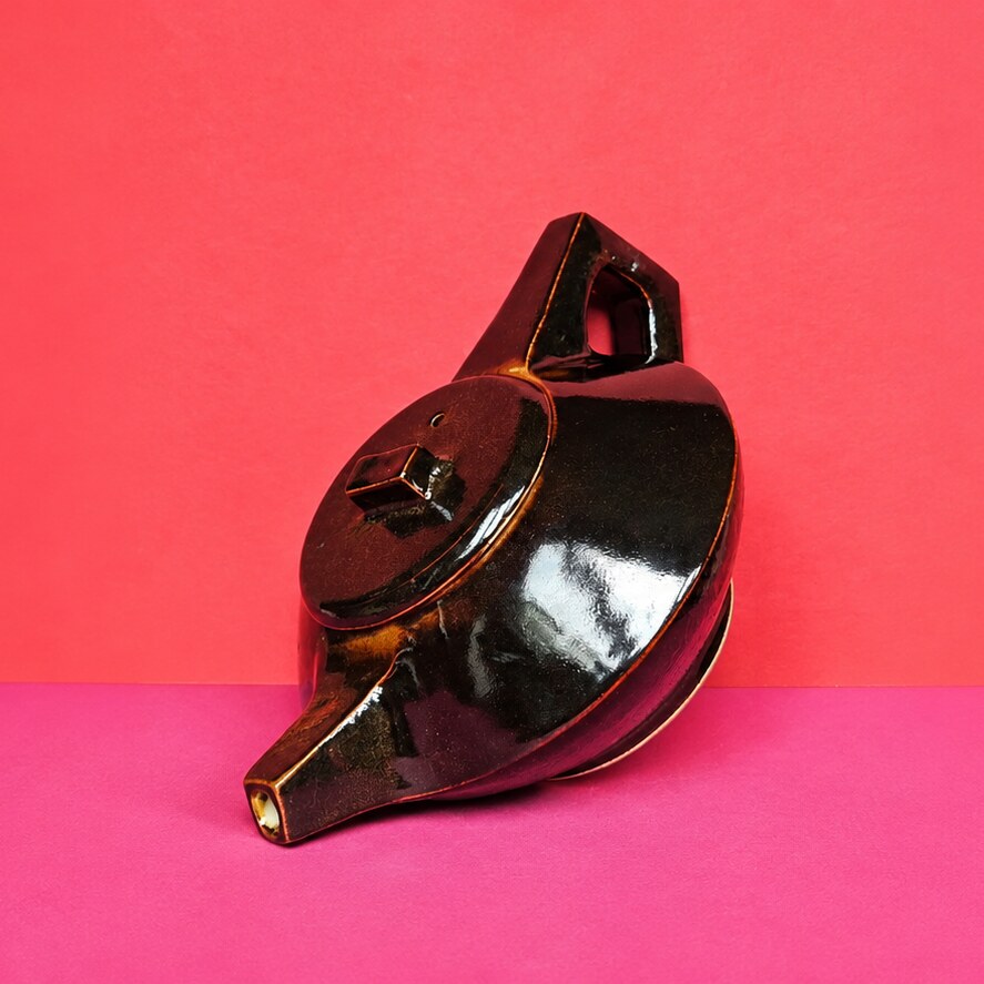 Théière « Marée Noire » : émail brun-noir brillant sur un papier de fond corail et rose vif